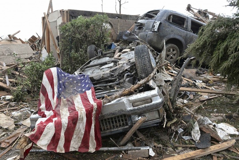Sebuah bendera Amerika terletak di atas sebuah puing mobil yang hancur diterjang tornado di Moore, Oklahoma, Senin (20/5) waktu setempat.    