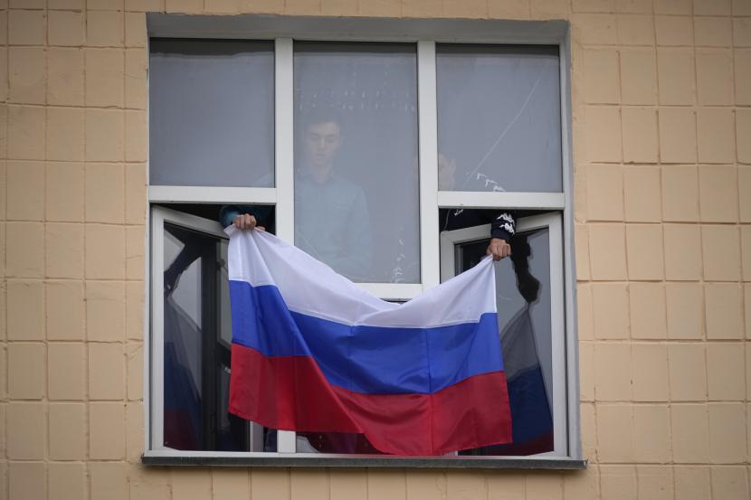  Sebuah bendera Rusia dikibarkan di Universitas Pedagogis di Luhansk, Republik Rakyat Luhansk yang dikendalikan oleh separatis yang didukung Rusia, Ukraina timur, Selasa 27 September 2022. Para Pendukung Rusia di Luar Negeri Berkumpul di Moskow