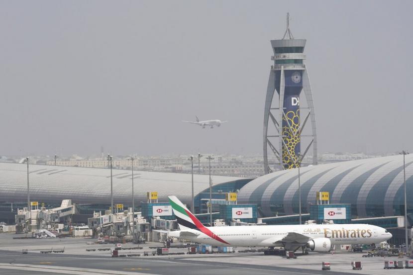 Sebuah Boeing 777 Emirates berdiri di pintu gerbang di Bandara Internasional Dubai saat pesawat lain bersiap untuk mendarat di landasan pacu di Dubai, Uni Emirat Arab, Rabu, 17 Agustus 2022. Bandara Internasional Dubai (DXB), Uni Emirat Arab mengincar 78 juta pelancong akan menggunakan jasa bandara tersibuk di dunia tersebut pada tahun ini. 