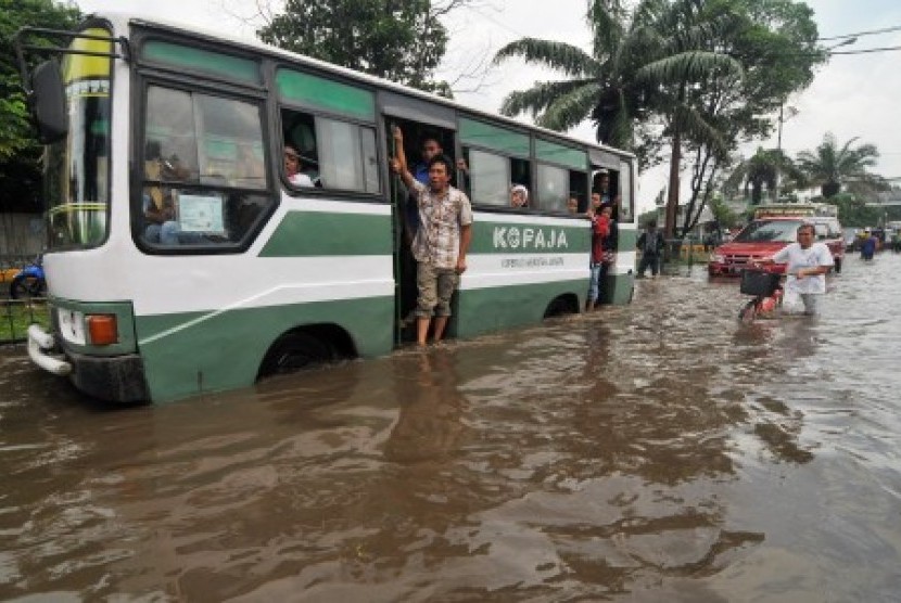 Sebuah bus Kopaja berusaha menerobos banjir di Jalan Daan Mogot, Jakarta Barat, Ahad (13/1). 