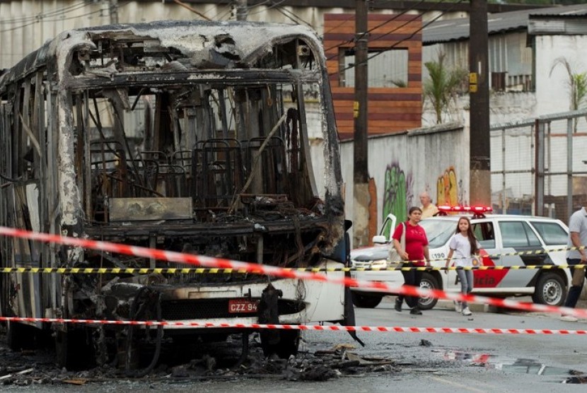Sebuah bus yang terbakar dikelingi garis polisi di pinggiran kota Sao Paulo, Brasil, Senin (12/11) 2012. Pembakaran menambah deretan panjang gelombang kekerasan yang telah menewaskan 31 orang selama akhir pekan. 