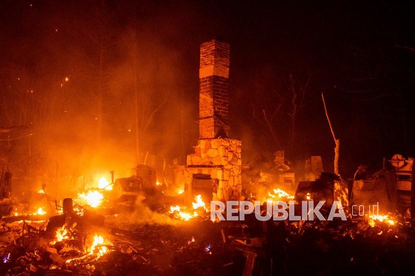   Sebuah cerobong asap berdiri di antara sisa-sisa tempat tinggal yang membara saat  api membakar Taman Nasional Angeles di utara Santa Clarita, California, Kamis (13/8).