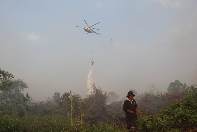 Sebuah helikopter melakukan pengeboman air (water bombing) terhadap lahan yang terbakar dekat permukiman warga di Kecamatan Dumai Timur, Kota Dumai, Riau, Kamis (7/3/2019).