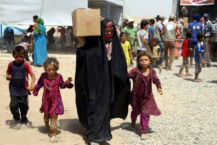 Sebuah keluarga Irak, yang terpaksa mengungsi akibat konflik, menerima bantuan di sebuah kamp pengungsian di Khazir, Erbil, Irak Utara, pada 23 Juli. 