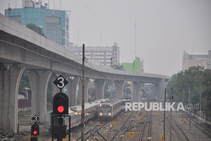 Sebuah kereta api Railink bandara Kualanamu melintas dengan latar belakang kota Medan yang diselimuti kabut asap di Sumatera Utara, Kamis (19/9/2019). 
