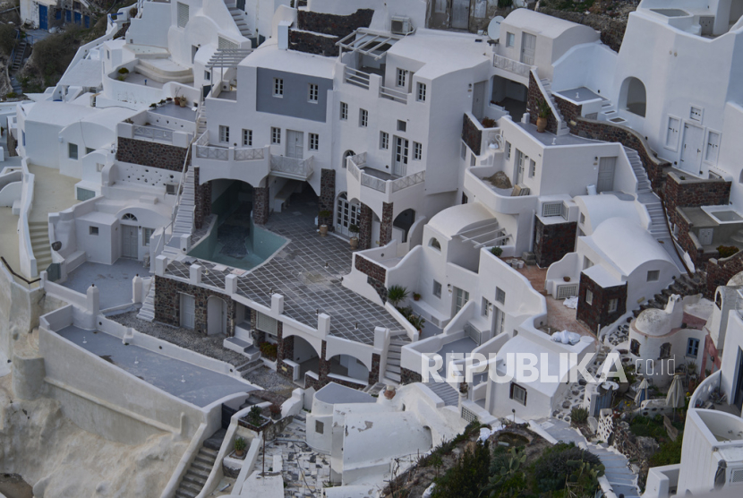 Sebuah kolam renang kosong terlihat di antara sekelompok bangunan di tepi tebing di kota Oia, di pulau Santorini yang dilanda gempa, Yunani, pada Selasa, 4 Februari 2025. 