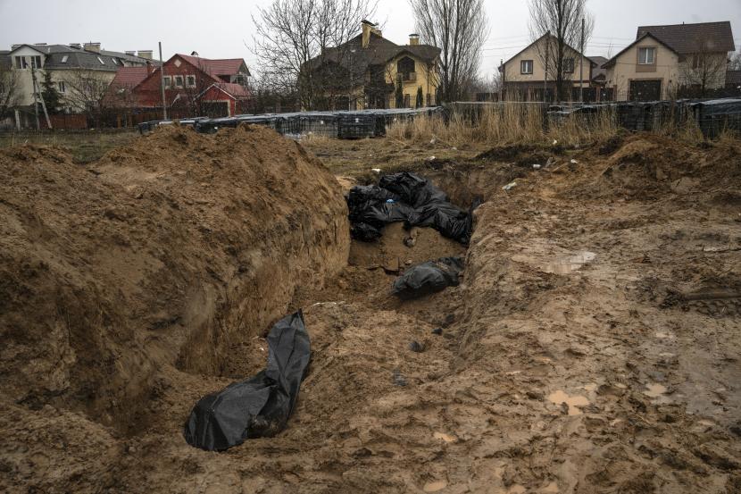 Sebuah kuburan massal di Bucha, di pinggiran Kyiv, Ukraina, Ahad, 3 April 2022. Pasukan Ukraina menemukan mayat-mayat brutal dan kehancuran yang meluas di pinggiran Kyiv, memicu seruan baru untuk penyelidikan kejahatan perang dan sanksi terhadap Rusia.