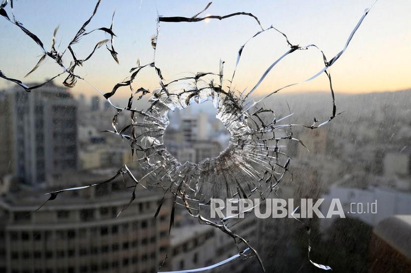  Sebuah lubang senjata terlihat di jendela sebuah gedung sehari setelah bentrokan di daerah Tayouneh di Beirut, Lebanon, 15 Oktober 2021. Sedikitnya enam orang tewas dan 20 terluka dalam unjuk rasa di Beirut yang diselenggarakan oleh gerakan Hizbullah dan Amal untuk menuntut pemecatan penyelidik utama ledakan di Beirut. 