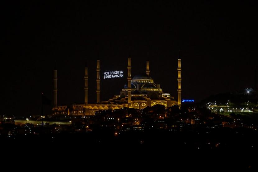 Sebuah mahya (pesan berpendar dari lampu yang digantung di antara menara masjid) berada di Masjid Camlica di Istanbul, Turki, 23 April 2020. Mahya umumnya berisi pesan Ramadhan, namun kini berisi pesan meminta umat berada di rumah.