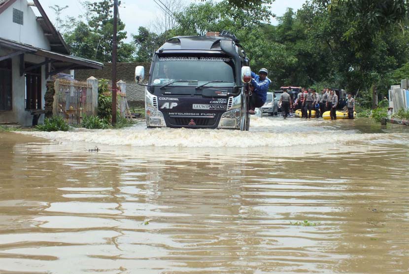 Sebuah mobil angkutan nekat menerobos jalan yang sudah tergenang air  Waduk Jatigede, Kabupaten Sumedang, Senin (15/2).  (foto : MgBDG_MJ05)