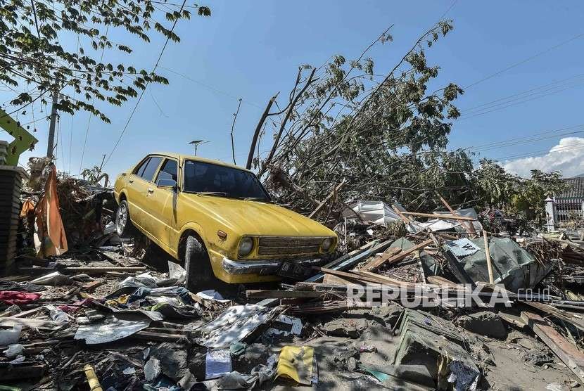 Sebuah mobil berada di reruntuhan bangunan yang hancur akibat tsunami pascagempa di wilayah Talise, Palu Barat, Sulawesi Tengah, Ahad (30/9).