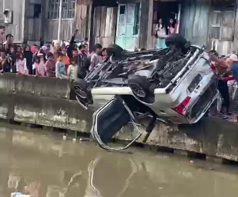 Sebuah mobil Daihatsu Xenia dirusak dan dicemplung warga ke sungai saat terjadi tawuran di Kelurahan 13 Ilir Kota Palembang, Sumatra Selatan, Ahad (13/3/2022). 