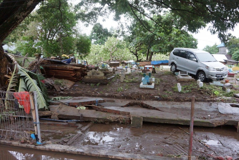 Sebuah mobil hanyut hingga tersangkut di kompleks pemakaman pascabanjir yang melanda sejumlah wilayah di Bima, Nusa Tenggara Barat, Kamis (22/12). 