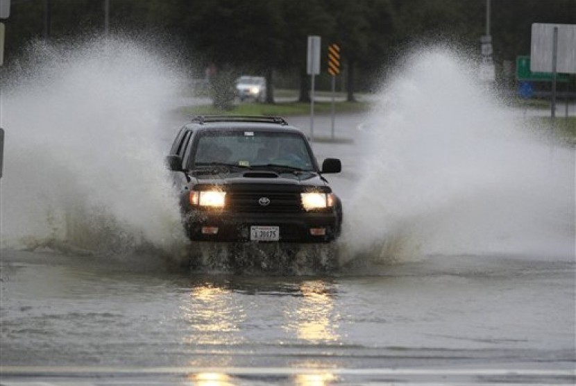 Sebuah mobil harus melewati genangan air yang tinggi di wilayah Ocean View di Norfolk, Virginia, Amerika Serikat (AS). Hujan dan angin yang disebabkan Badai Sandy telah menyerang sepanjang wilayah timur laut AS.