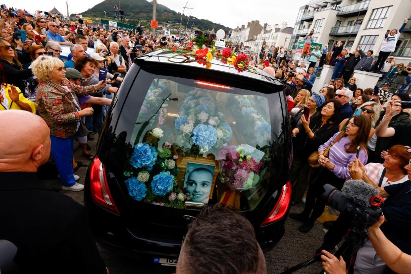 Sebuah mobil jenazah yang membawa peti jenazah penyanyi Irlandia Sinead O Connor lewat selama prosesi pemakamannya di mana para penggemar berbaris di jalan untuk mengucapkan selamat tinggal terakhir padanya di Bray, Irlandia, 8 Agustus 2023. 