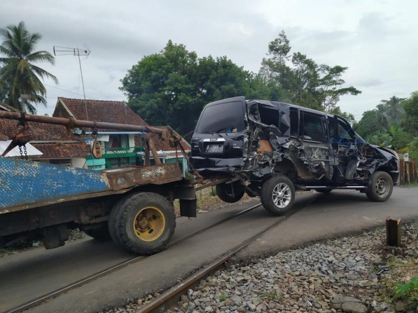 Sebuah mobil rusak akibat tertabrak kereta diderek melintasi pelintasan sebidang tanpa palang pintu di Manonjaya, Kabupaten Tasikmalaya, Selasa (15/12).