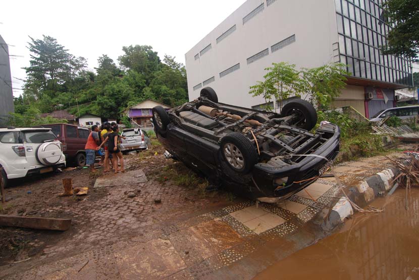  Sebuah mobil terbalik akibat terseret bajir di kawasan kantor Walikota Manado, Sulawesi Utara, Kamis (16/1).     (Antara/Fiqman Sunandar)