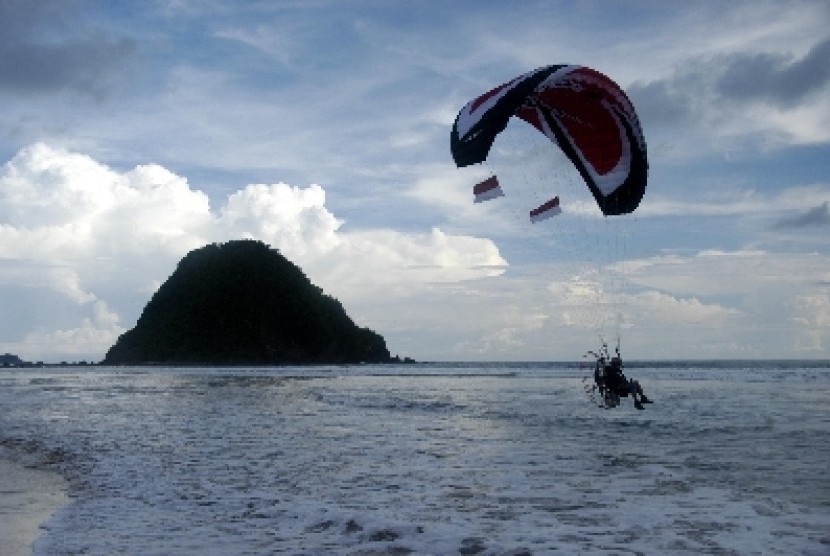Sebuah paramotor terbang di atas pantai (ilustrasi).
