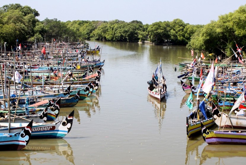 Sebuah perahu melintas di samping puluhan perahu nelayan yang bersandar di sungai kawasan Cemandi, Sedati, Sidoarjo, Jawa Timur, Senin (8/7/2019). 