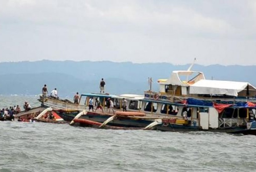 Sebuah perahu tongkang menyelamatkan penumpang kapal motor MBCA Kim-Nirvana (kiri) yang tenggelam setelah meninggalkan pelabuhan Ormoc City, Manila, Filipina, Kamis (2/7).