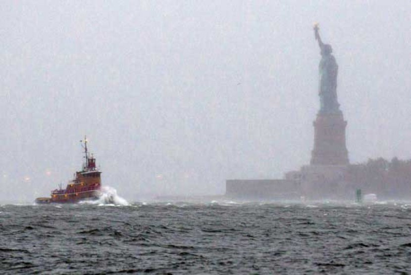 Sebuah perahu tug melintasi deburan ombak dekat Patung Liberty di New York, Senin (29/10) waktu setempat.     (Craig Ruttle/AP)  