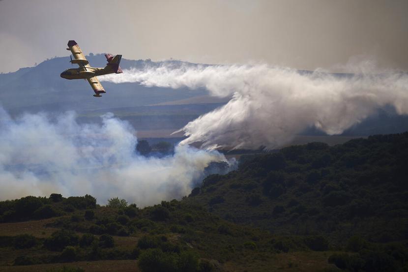 Sebuah pesawat pemadam kebakaran menjatuhkan penghambat api di area terbakar San Martin de Unx di Spanyol utara, Minggu, 19 Juni 2022. Petugas pemadam kebakaran di Spanyol berjuang untuk menahan kebakaran hutan di beberapa bagian negara yang mengalami gelombang panas yang tidak biasa pada tahun ini.