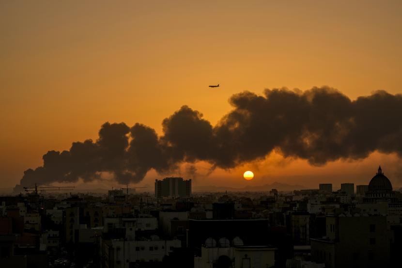Sebuah pesawat penumpang terbang di atas api yang membara di depot minyak Saudi Aramco setelah serangan pemberontak Houthi Yaman, menjelang balapan Formula Satu saat matahari terbit di Jeddah, Arab Saudi, Sabtu, 26 Maret 2022.