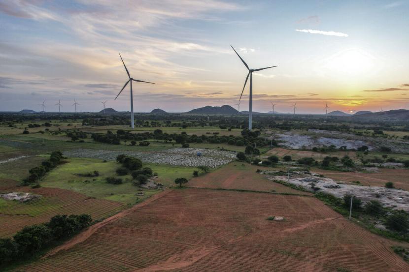 Sebuah peternakan kincir angin bekerja saat matahari terbenam di distrik Anantapur, Andhra Pradesh, India, Rabu, 14 September 2022. India berinvestasi besar-besaran dalam energi terbarukan dan telah berkomitmen untuk memproduksi 50?yanya dari sumber energi bersih pada tahun 2030.