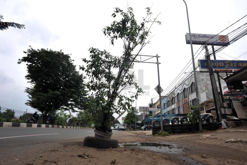 Sebuah pohon dipasang untuk menutupi lubang jalanan di jalan kalimalang, bekasi, jawa barat, Selasa (25/4).