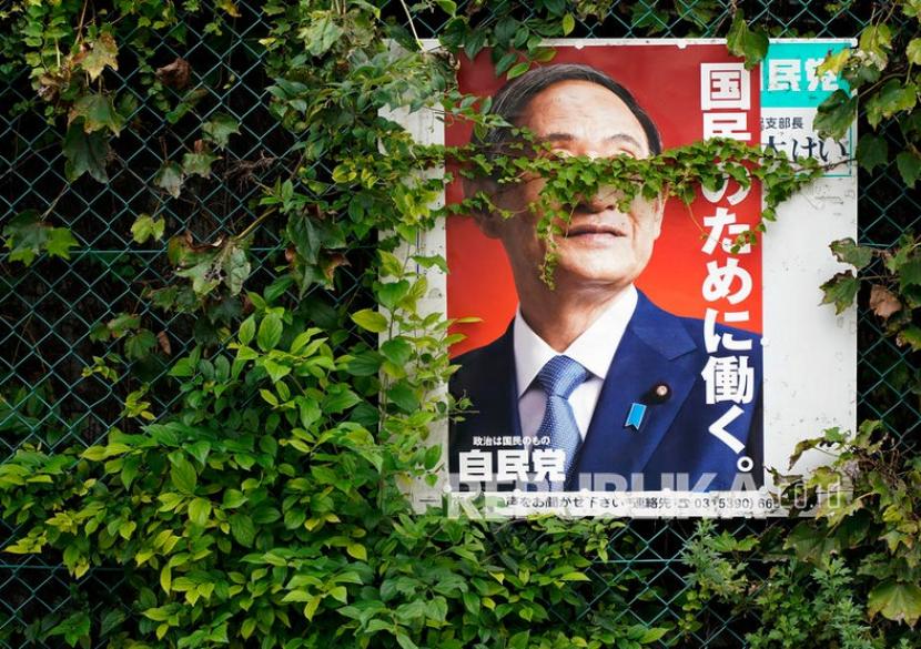 Sebuah poster yang ditutupi vegetasi menunjukkan Perdana Menteri Jepang Yoshihide Suga yang akan keluar di Tokyo, Jepang, 17 September 2021. Jepang akan melakukan pemilihan perdana menteri baru di negara itu pada November.  