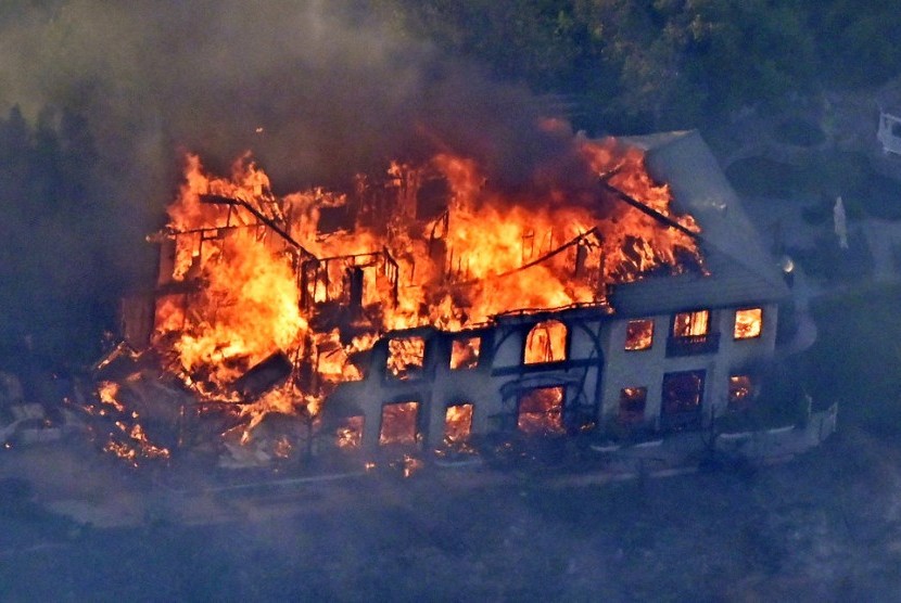Sebuah rumah dilalap api dalam kebakaran di Kalifornia. Kebakaran hutan mungkin akan lebih sering terjadi akibat perubahan iklim.