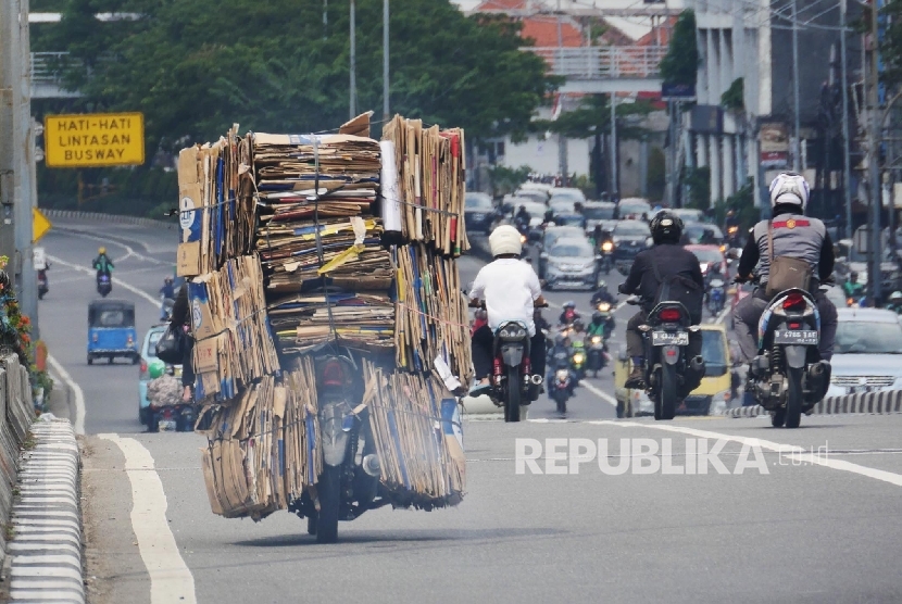  Sebuah sepeda motor dengan bermuatan tumpukan kardus bekas melintas di kisaran fly over Senen Jakarta, Selasa (4/7). 