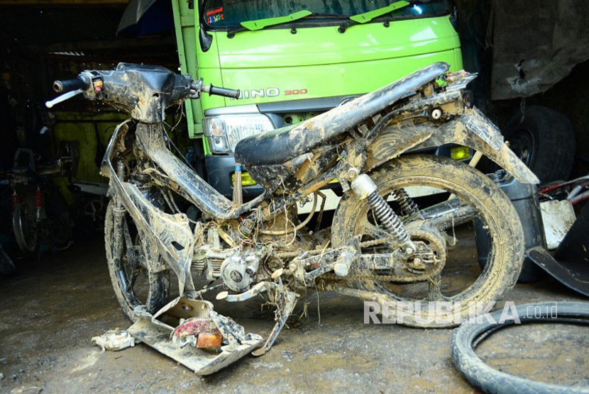 Sebuah sepeda motor rusak dan berlumpur akibat terseret banjir bandang 