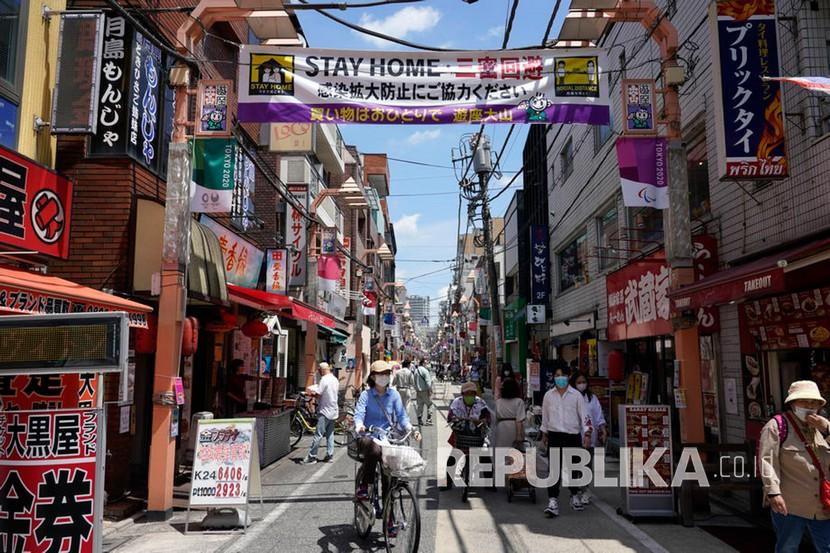 Sebuah spanduk imbauan agar orang-orang tinggal di rumah untuk menekan penyebaran COVID-19 dan pandemi coronavirus di kawasan pertokoan, Tokyo, Jepang, Senin (11/5). Ilustrasi.