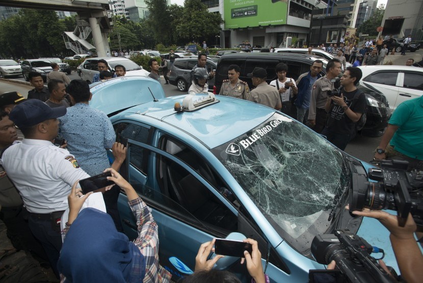 Sebuah taksi dirusak oleh para pengemudi ojek berbasis online di jalan Rasuna Said, Jakarta, Selasa (22/3).