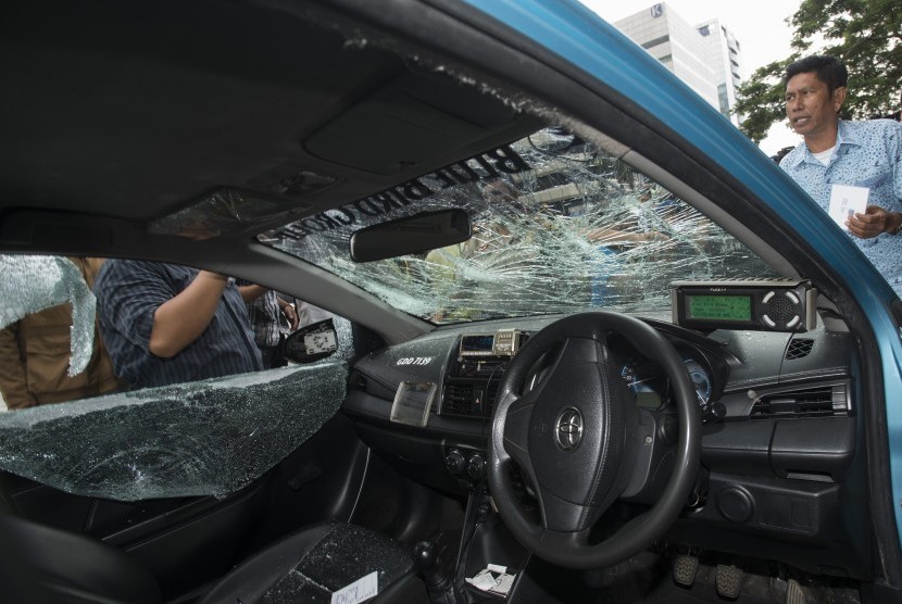 Sebuah taksi dirusak oleh para pengemudi ojek daring di Jalan Rasuna Said, Jakarta, Selasa (22/3).