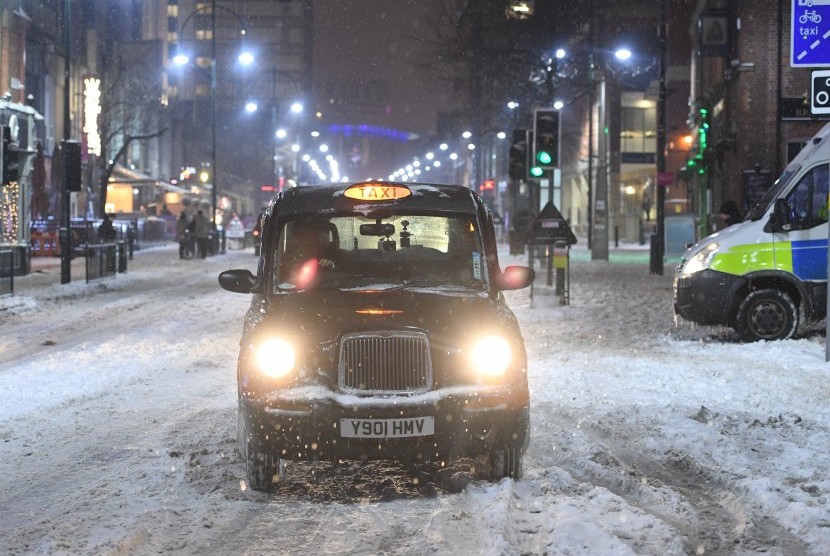 Sebuah taxi melintas di jalan Kota Birmingham, Inggris yang dipenuhi salju pada Jumat (2/3).