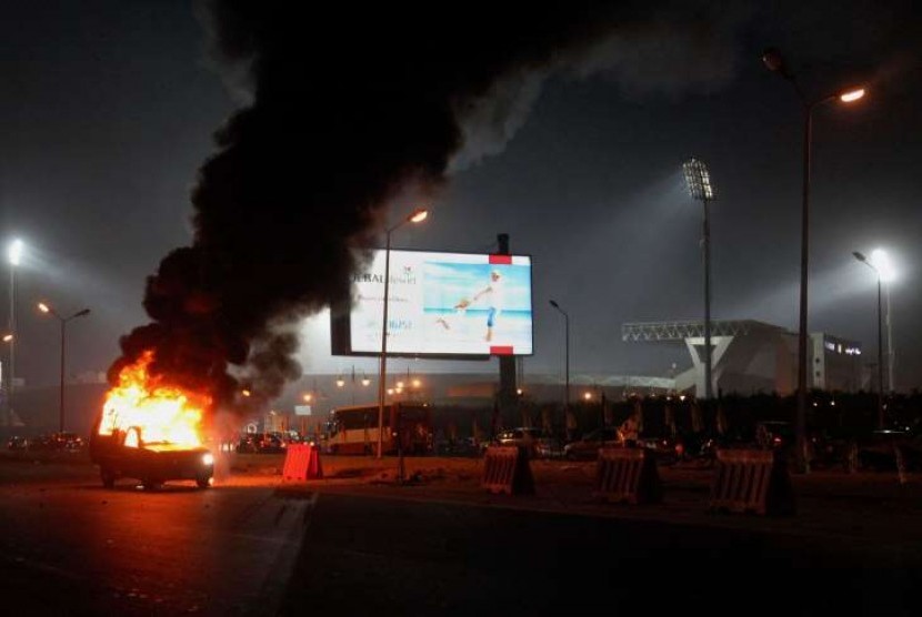Sebuah truk terbakar akibat bentrok pasukan keamanan Mesir dengan pendukung klub Zamalek di luar Air Defense Stadium di Kairo, Mesir, Ahad (8/2)