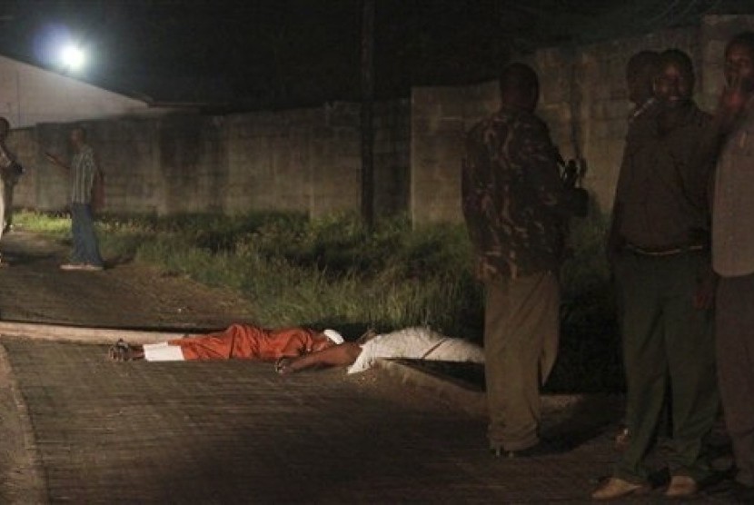 Security forces stand next to the bodies of slain muslim cleric Abubakar Shariff Ahmed, center, and another man whose identity has not yet been established, center-left, on a highway in Mombasa, Kenya Tuesday, April 1, 2014. 