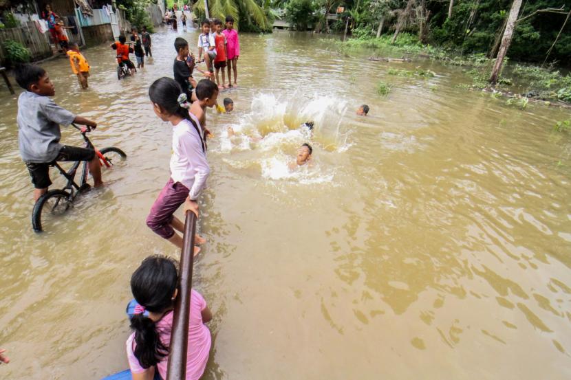 Sejumlah anak berenang di dalam banjir yang merendam Desa Ampeh, Kecamatan Tanah Luas, Aceh Utara, Selasa (9/11). Banjir akibat luapan sungai yang tidak mampu menampung tingginya intensitas hujan itu menerjang Tiga kecamatan di Aceh Utara dan ratusan jiwa warga dilaporkan mulai mengungsi.