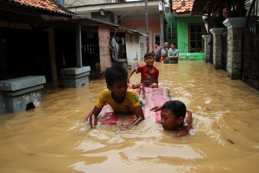 Sejumlah anak bermain air banjir yang merendam kawasan permukiman penduduk Cililitan Kecil, Jakarta, Jumat (26/4/2019).