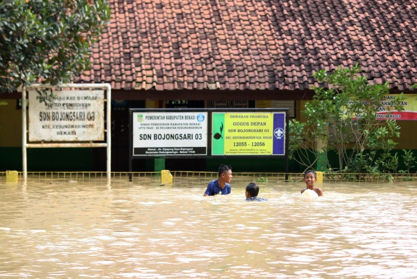 Sejumlah anak bermain air di area gedung sekolah yang terendam banjir di kawasan pemukiman penduduk bantaran Sungai Citarum, Kedungwaringin, Kabupaten Bekasi, Jawa Barat, Senin (14/11). 