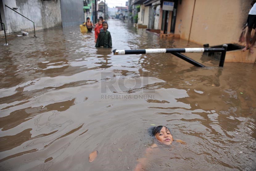 Sejumlah anak bermain saat banjir merendam perumahan Jatikramat Indah di Bekasi, Jawa Barat, Jumat (28/3).