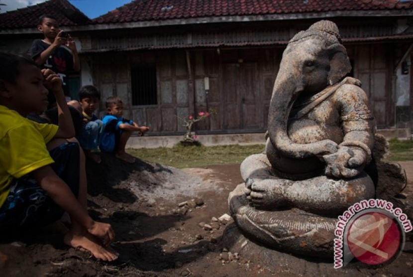 Sejumlah anak melihat arca Ganesha yang ditemukan, di Plakaran Kidul, Banguntapan, Bantul, Yogyakarta, Rabu (31/7). Peninggalan purbakala dengan tinggi 138 cm tersebut ditemukan warga, Selasa (30/7) ketika melakukan proses pembangunan irigasi di kawasan it