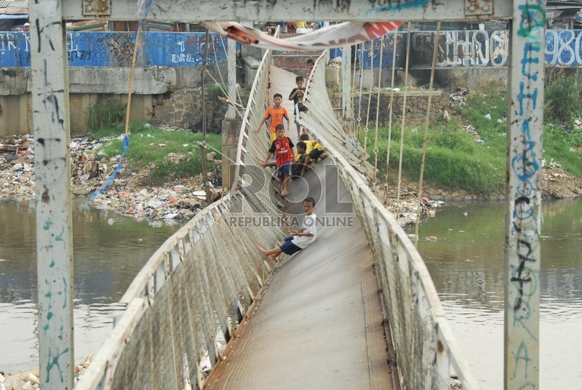  Sejumlah anak melintasi jembatan gantung miring yang melintang di atas Kanal Banjir Barat di kawasan Grogol petamburan, Jakarta Barat, Kamis (12/6). ( Republika/Rakhmawaty La'lang)