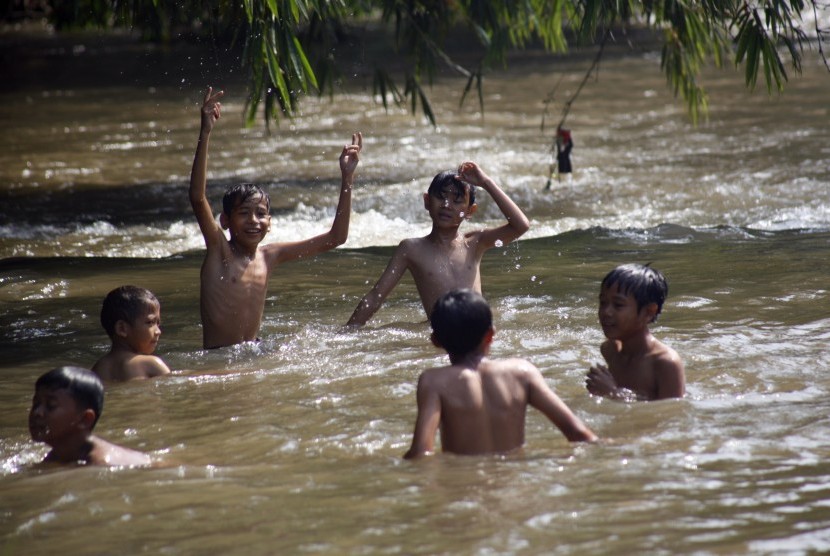 Sejumlah anak memanfaatkan hari libur dengan bermain di aliran Sungai Ciliwung, Depok, Jawa Barat, Jumat (19/4/2019).