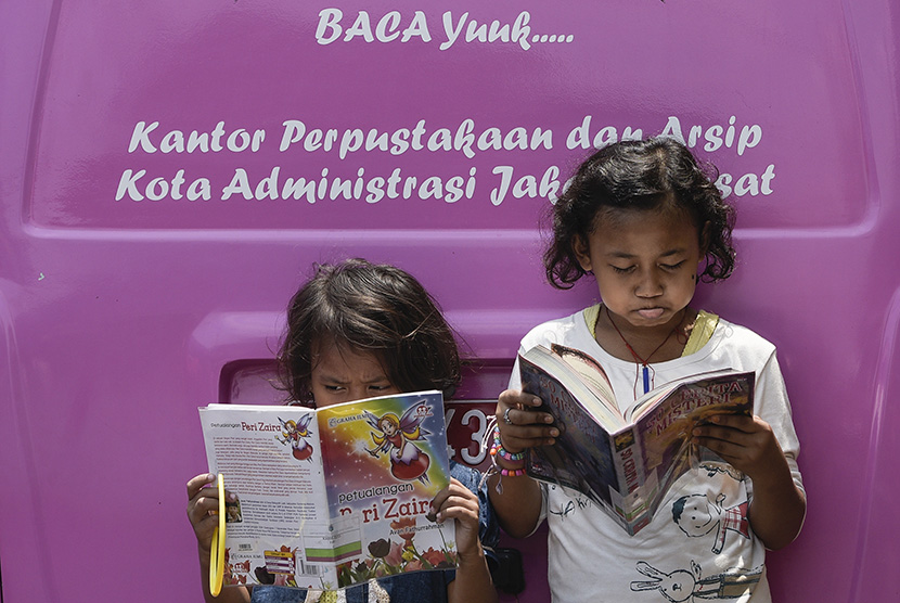 Sejumlah anak membaca buku yang disediakan gratis di mobil perpustakaan keliling, Tanah Abang, Jakarta Pusat, Ahad (11/10).   (Antara/Sigid Kurniawan)