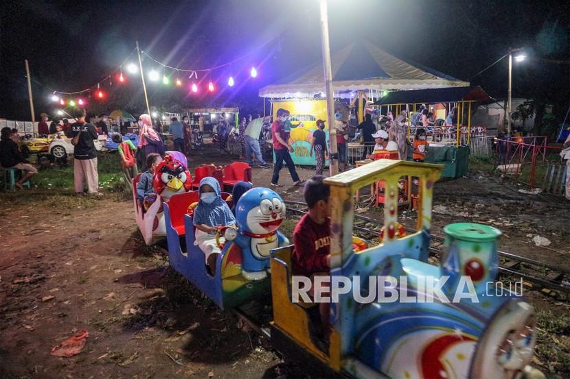 Sejumlah anak mengendarai wahana permainan pada pasar malam di Depok, Jawa Barat, Ahad (26/12/). Wahana permainan pada pasar malam menjadi alternatif hiburan warga pada libur Natal dan libur akhir tahun. 