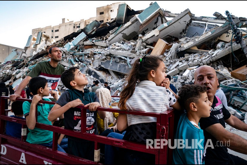  Sejumlah anak Palestina mengendarai kendaraan terbuka melewati reruntuhan gedung al-Jalaa yang hancur oleh serangan udara Israel, Gaza, Jumat (21/5) waktu setempat.  Sejumlah media internasional menempati gedung al-Jalaa, termasuk kantor berita Associated Press yang telah berkantor di sana selama 15 tahun.