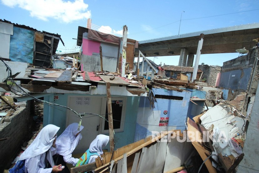 Sejumlah anak sekolah melewati rumah-rumah yang dibongkar sendiri oleh pemiliknya di lokasi proyek pembangunan Rumah Deret Tamansari, Kota Bandung 